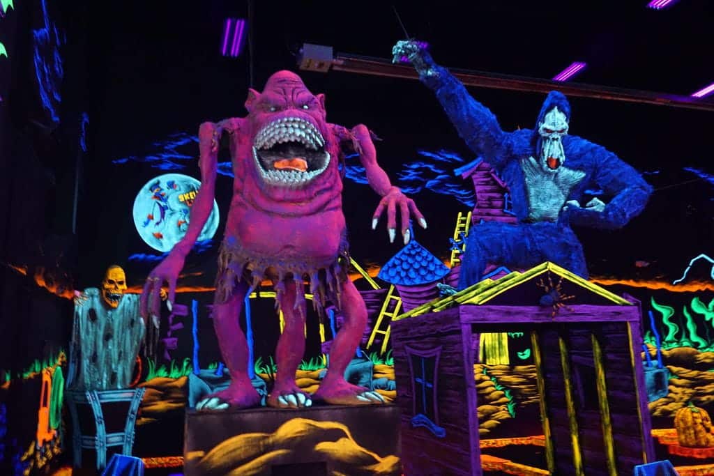 Giant neon decorations of monsters at a monster mini golf location.