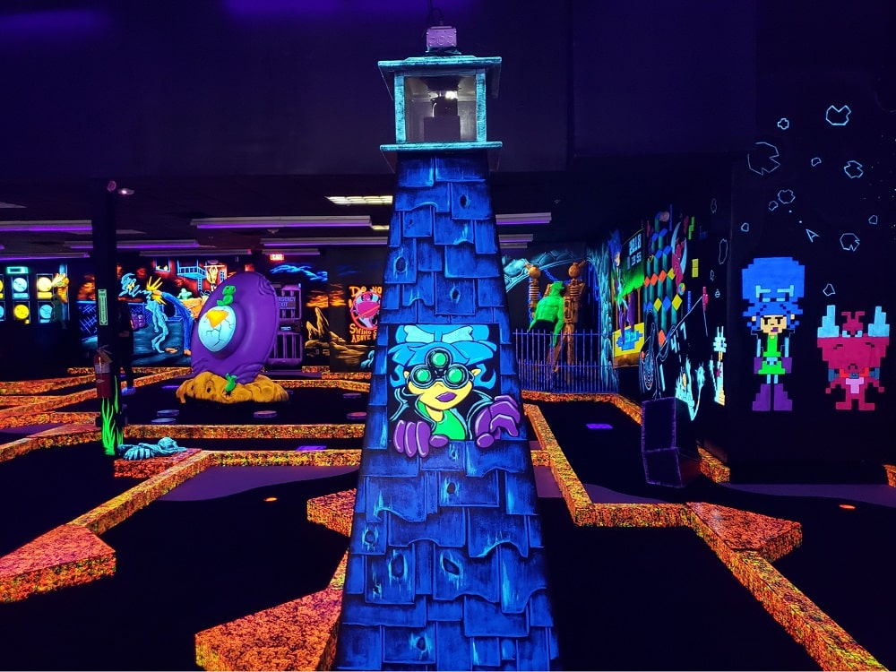 A glow-in-the-dark lighthouse at a monster mini golf location.