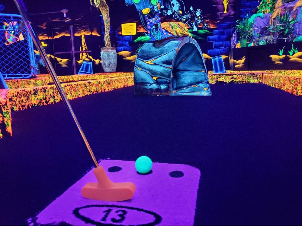 Monster Mini Golf 9 A putter and a green golf ball under neon lights at monster mini golf.